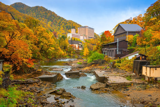 Autumn trees and hot-spring buildings beside the river in Jozankei.